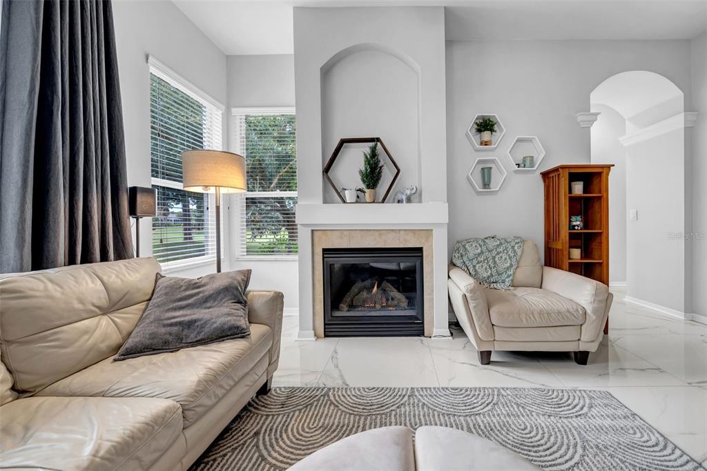 A living room features a fireplace, white tile floors, a leather sofa, and an armchair — 4455 GEVALIA DRIVE, BROOKSVILLE, FL