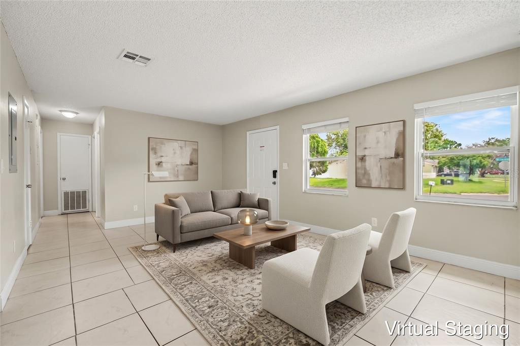 An empty room with beige walls, white tile flooring, a white door, and two windows — 140 GUAYMAS DRIVE, KISSIMMEE, FL