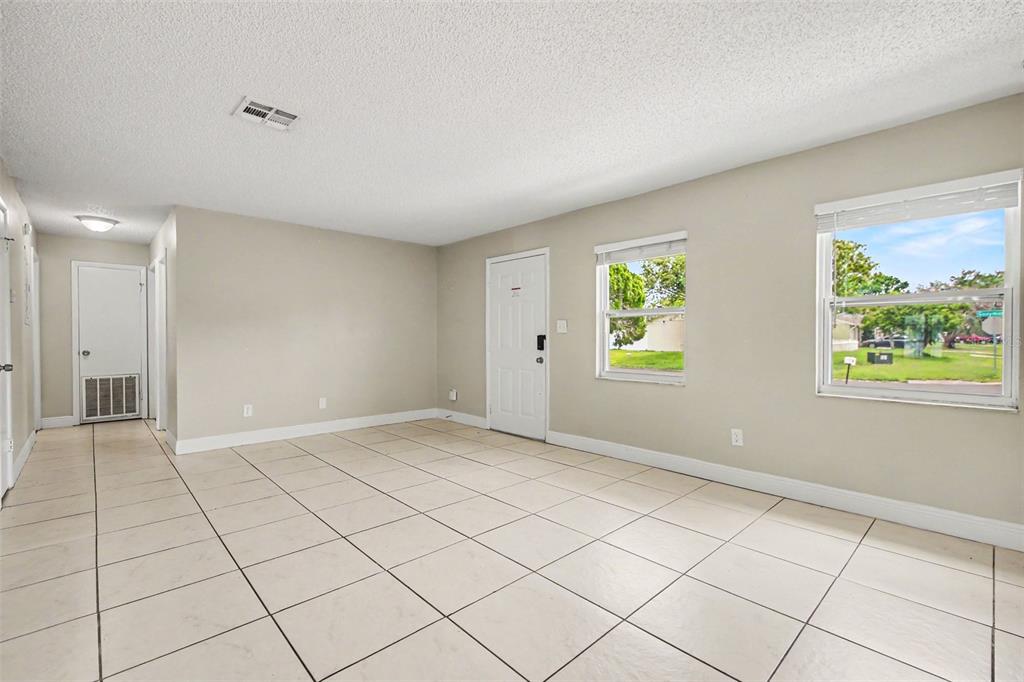 A spacious room with light-colored tile flooring, white walls, and a view into another area — 140 GUAYMAS DRIVE, KISSIMMEE, FL