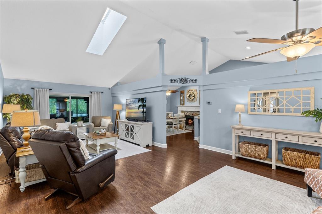 A living room with vaulted ceilings, a skylight, blue walls, and dark wood flooring — 633 PUGH STREET, LAKE MARY, FL