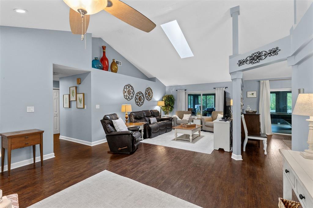 A spacious living room features vaulted ceilings, dark wood flooring, and a neutral color palette — 633 PUGH STREET, LAKE MARY, FL