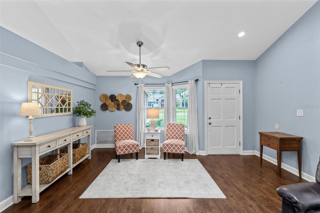 A light blue living room features a white console table, two patterned chairs, and wood flooring — 633 PUGH STREET, LAKE MARY, FL