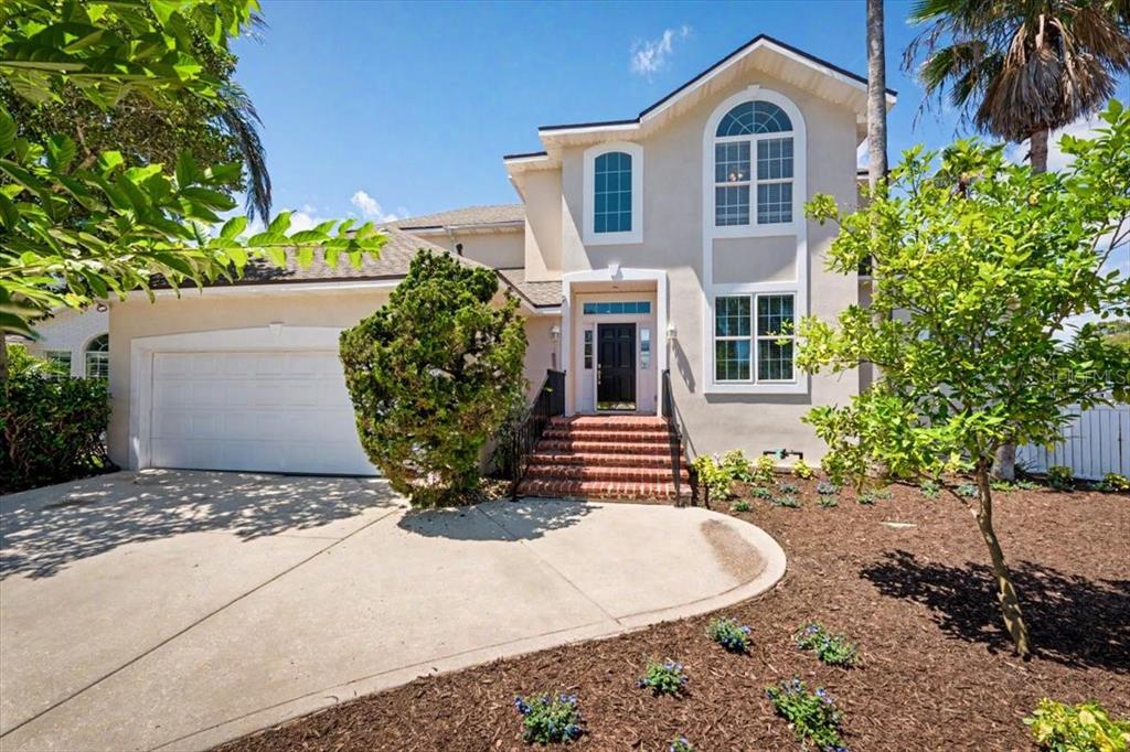 A two-story house with a beige exterior, a white garage door, and brick front steps — 4422 TIDEVIEW DRIVE, JACKSONVILLE, FL