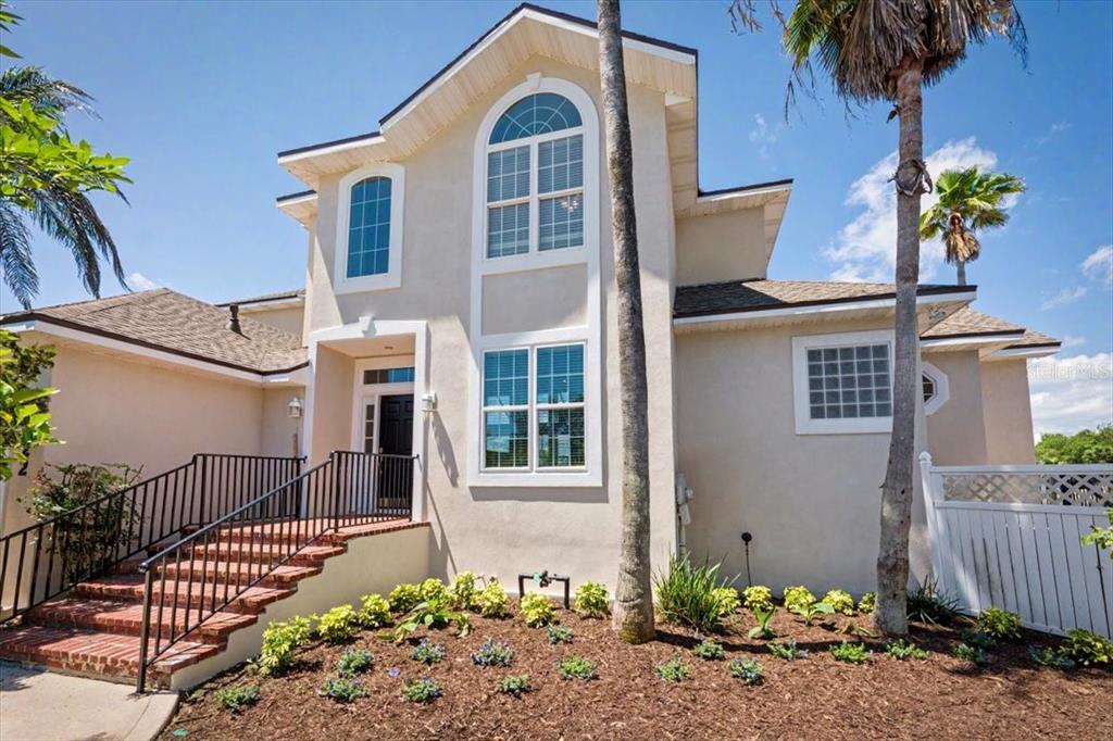 A two-story beige house features a brick staircase, arched windows, and a palm tree — 4422 TIDEVIEW DRIVE, JACKSONVILLE, FL