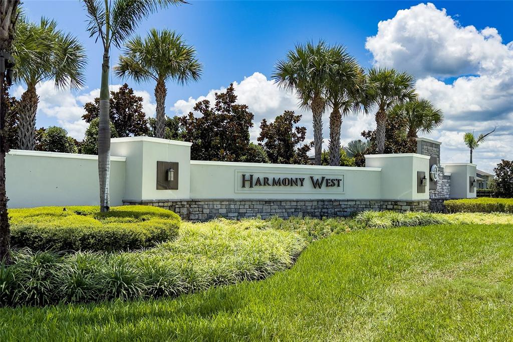 A stone and stucco monument sign for Harmony West stands in a landscaped residential area — 2822 HARMONIA HAMMOCK RD, HARMONY, FL