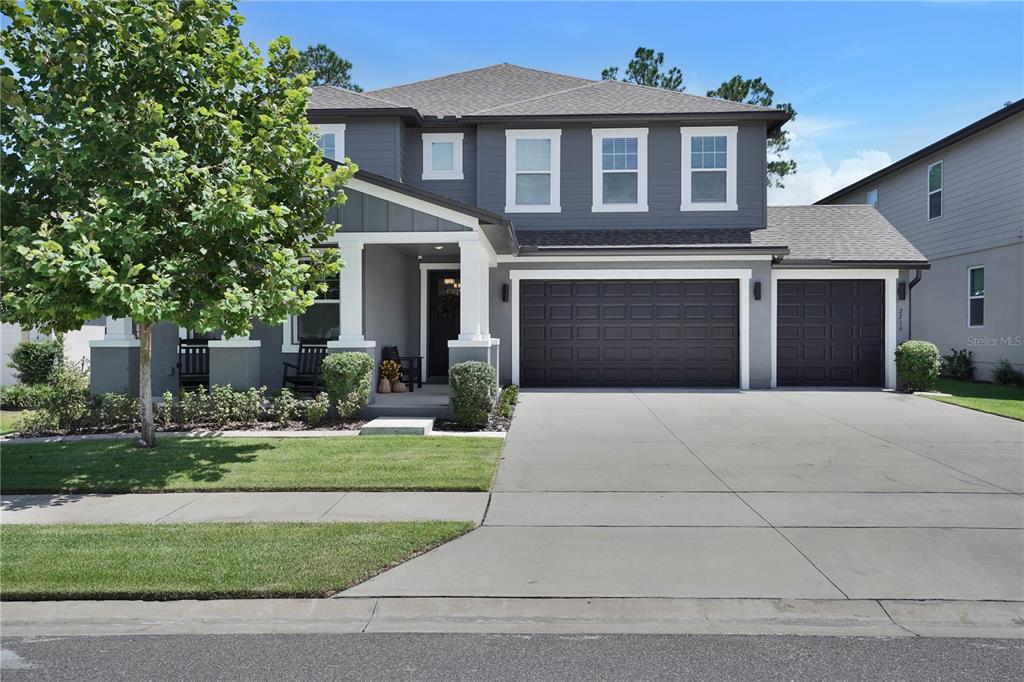 A two-story gray house with a three-car garage and a covered front porch — 2210 GOLD DUST DRIVE, MINNEOLA, FL
