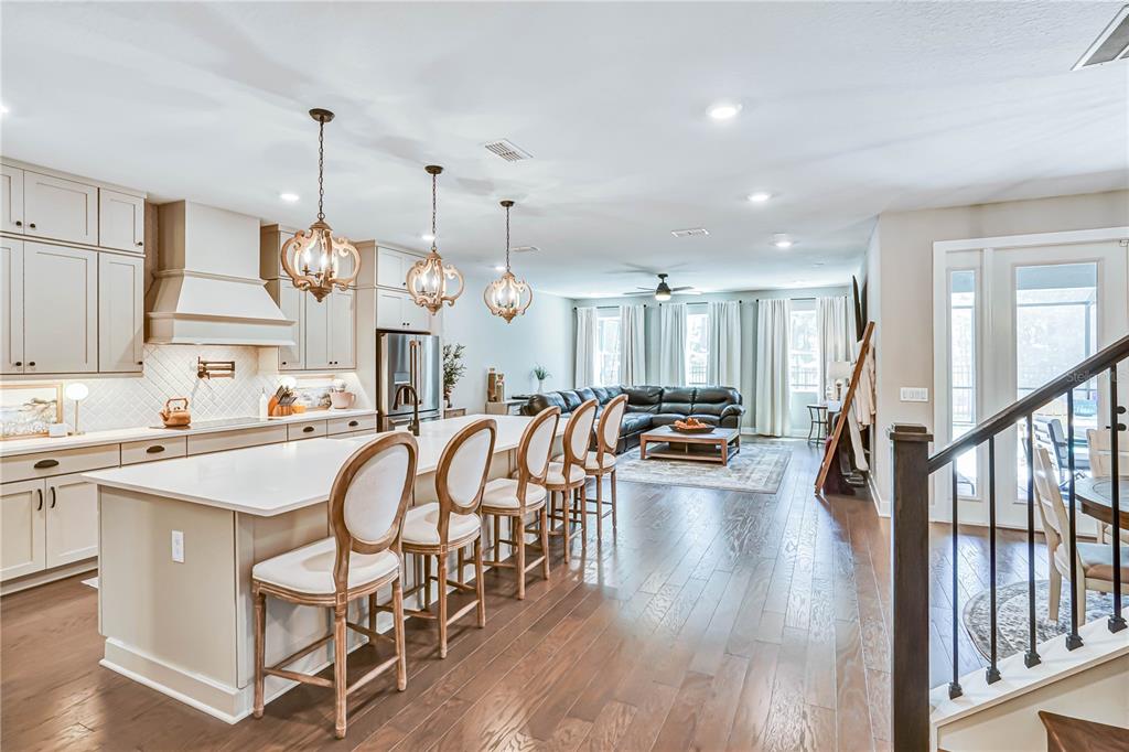 A kitchen with a large island and bar stools opens into a living room area — 2210 GOLD DUST DRIVE, MINNEOLA, FL