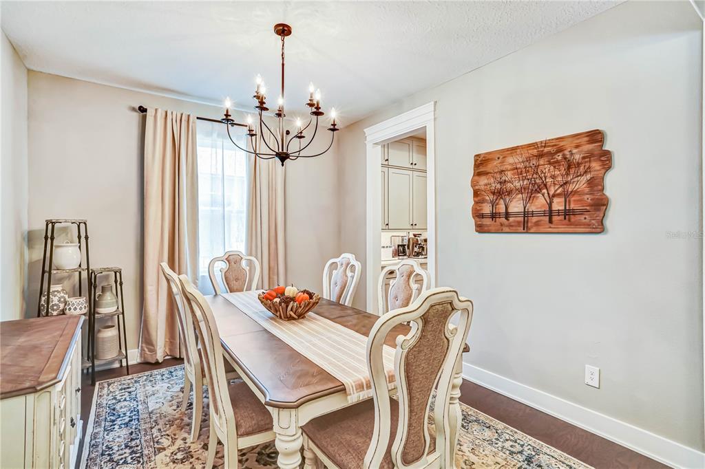 A dining room features a wooden table, six chairs, a chandelier, and wall-mounted art — 2210 GOLD DUST DRIVE, MINNEOLA, FL