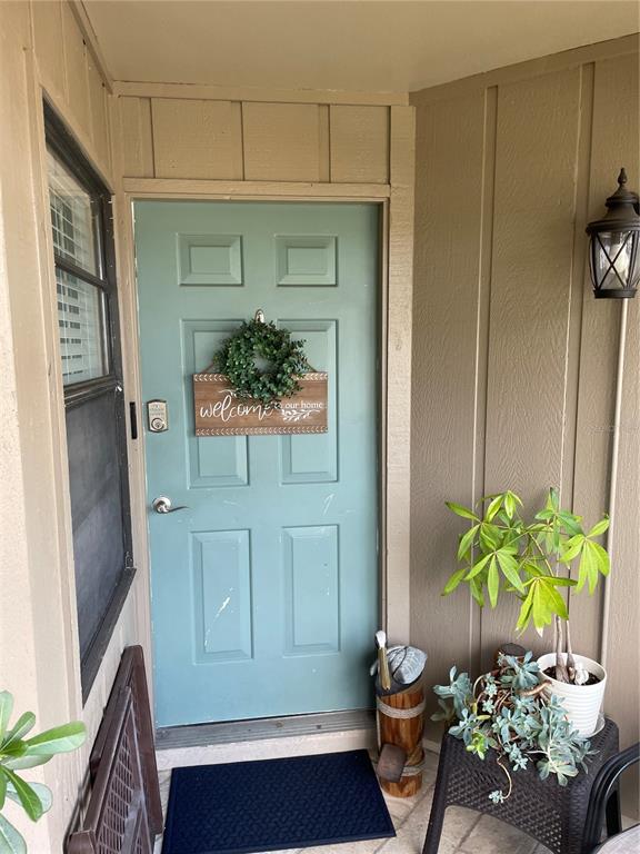 A teal front door with a wreath and welcome sign sits on a covered porch — 2131 RIDGE ROAD S UNIT 2, LARGO, FL