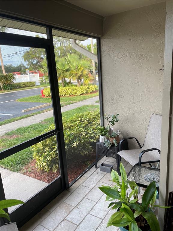 A screened-in patio features a chair, small tables, potted plants, and a view outside — 2131 RIDGE ROAD S UNIT 2, LARGO, FL