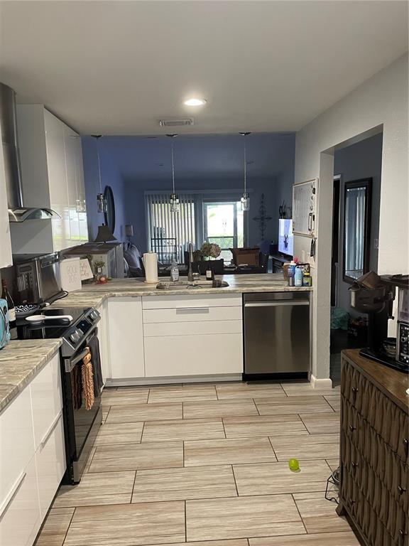 A kitchen features white flat-panel cabinets, stainless steel appliances, and light-toned wood-look floor tiles — 2131 RIDGE ROAD S UNIT 2, LARGO, FL