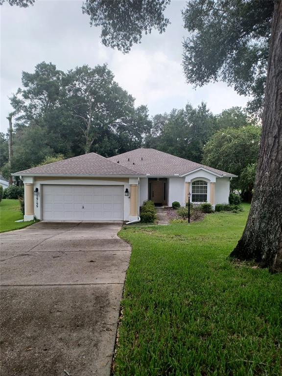 A single-story house with a white stucco exterior, a two-car garage, and a shingled roof — 19199 SW 92ND LOOP, DUNNELLON, FL