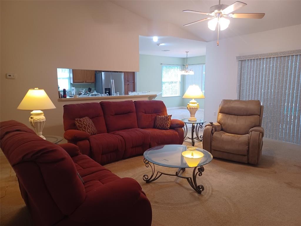 A living room features red sofas, a tan recliner, a glass coffee table, and carpeted floors — 19199 SW 92ND LOOP, DUNNELLON, FL