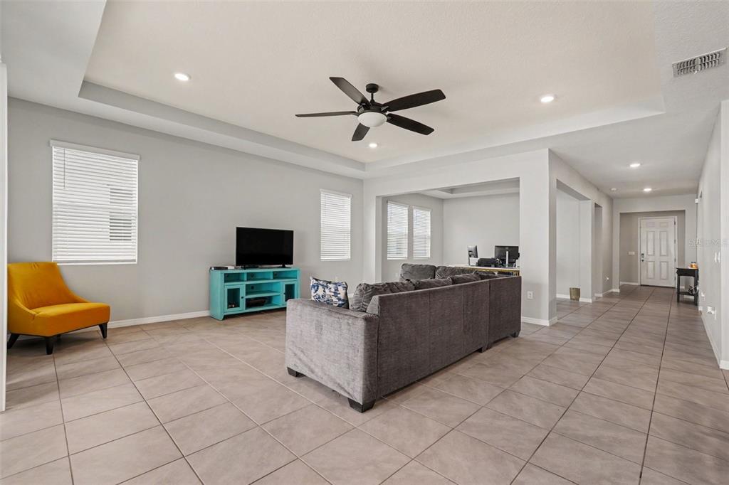 A living room features a gray sectional sofa, a teal media console, and tile flooring — 528 OCEAN SPRAY DRIVE, RUSKIN, FL