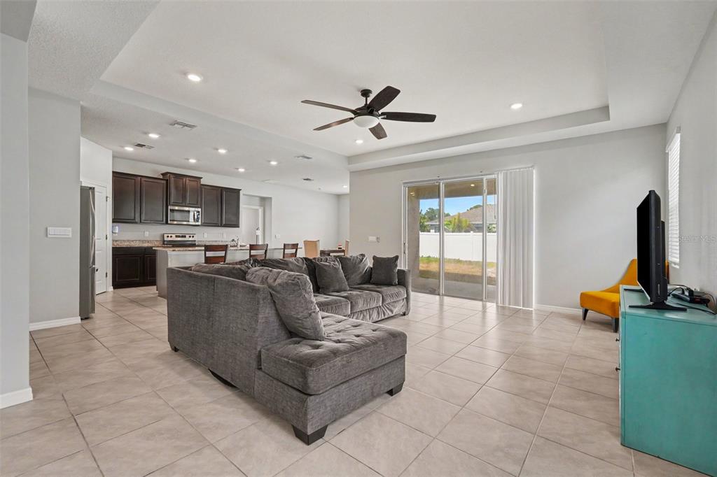A living room with tile floors, a grey sectional sofa, and an open-concept kitchen — 528 OCEAN SPRAY DRIVE, RUSKIN, FL