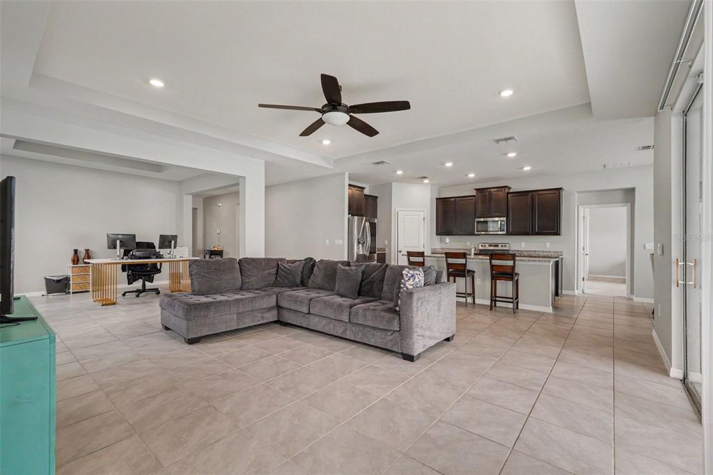 An open-concept living room and kitchen with tile flooring, a gray sectional, and dark cabinetry — 528 OCEAN SPRAY DRIVE, RUSKIN, FL