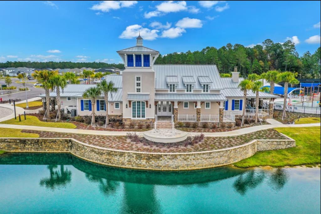 An aerial view of a coastal-style community clubhouse with a metal roof and stone wall — 165 WATER ELM WALK, ST AUGUSTINE, FL