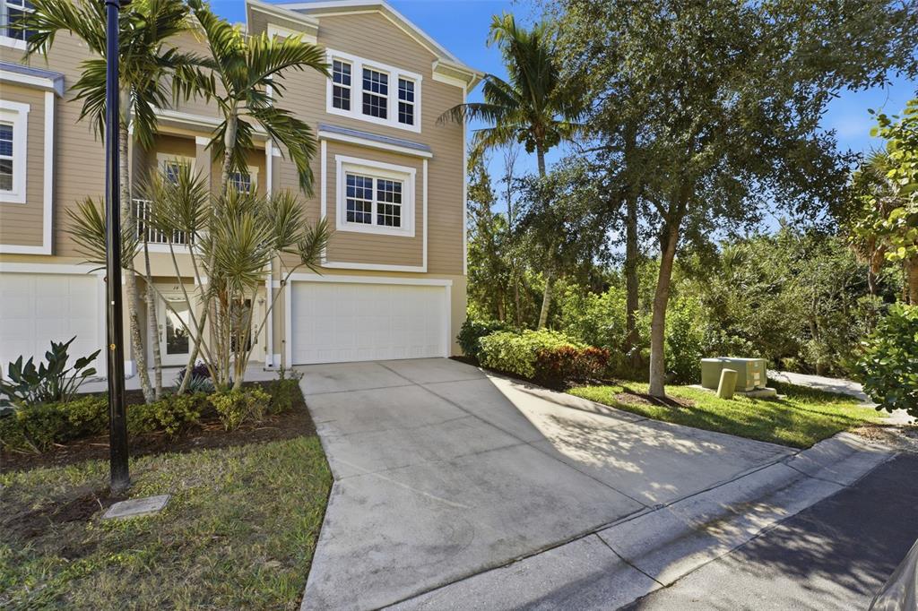 A tan three-story townhouse features a two-car garage, a concrete driveway, and palm trees — 10311 LANDS END CIRCLE UNIT 13, PLACIDA, FL