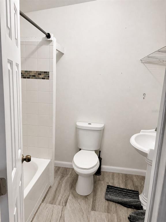 A bathroom features a white pedestal sink, a toilet, and a shower-tub combo with tile — 16 N CHRISTIANA AVENUE, APOPKA, FL