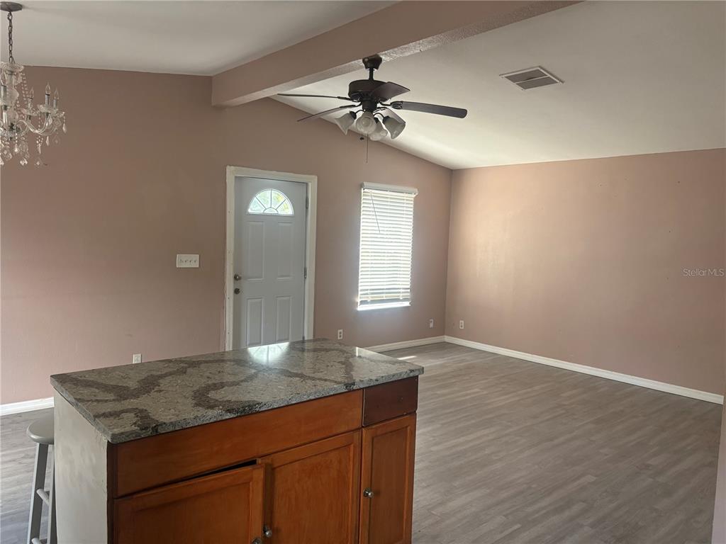 A kitchen island with a granite countertop sits in a room with light-colored walls — 16 N CHRISTIANA AVENUE, APOPKA, FL