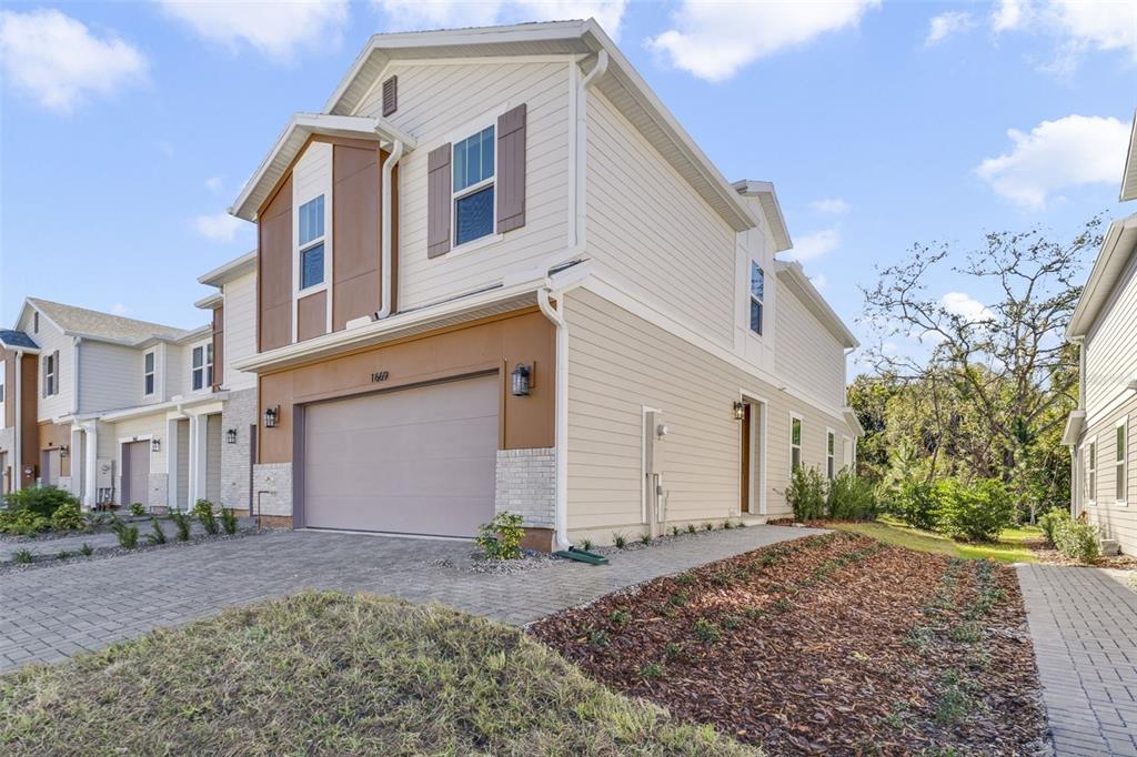 A two-story suburban house with a beige exterior, a two-car garage, and a paved driveway — 1669 GREENLEAF WOODS COVE, OVIEDO, FL