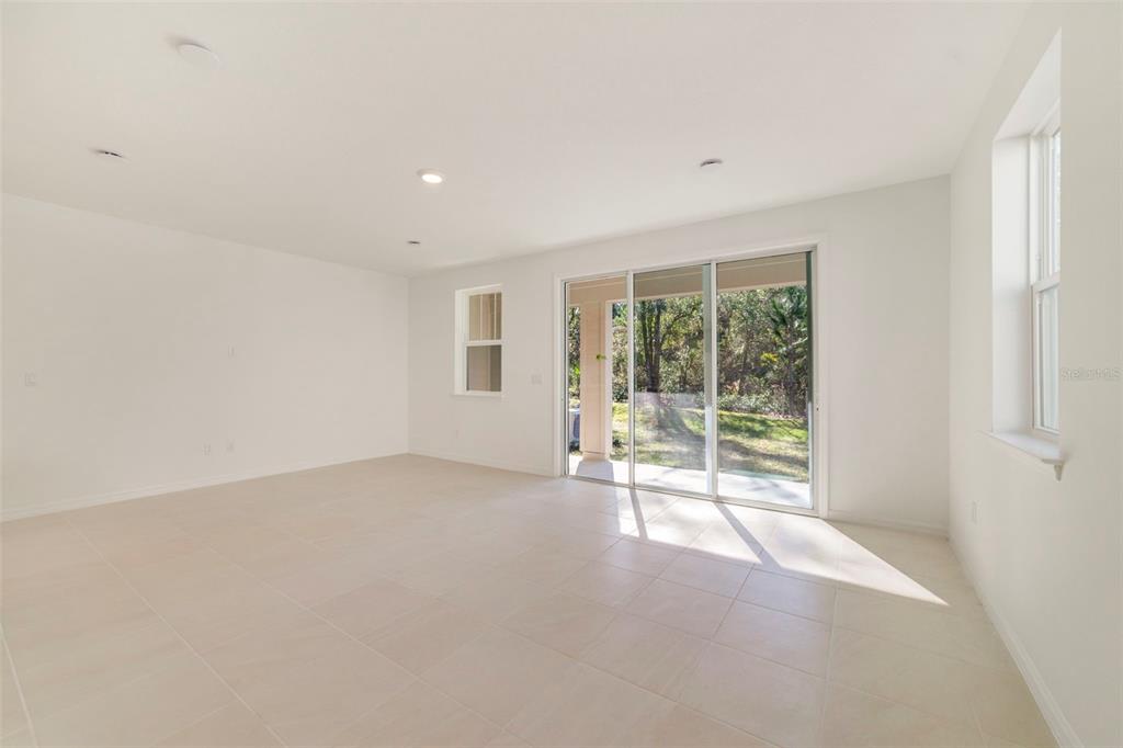 An empty room with light-colored tile flooring, white walls, recessed lighting, and sliding glass doors — 1669 GREENLEAF WOODS COVE, OVIEDO, FL