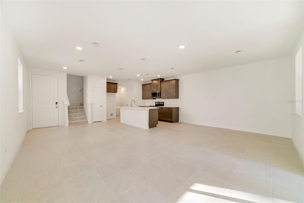 An open-concept kitchen and living area features tile flooring, white walls, and dark wood cabinetry — 1669 GREENLEAF WOODS COVE, OVIEDO, FL