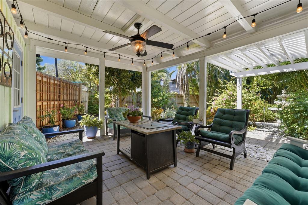 A covered patio features a fire pit table, outdoor seating, and string lights on pavers — 3424 OLD OAK DRIVE, SARASOTA, FL