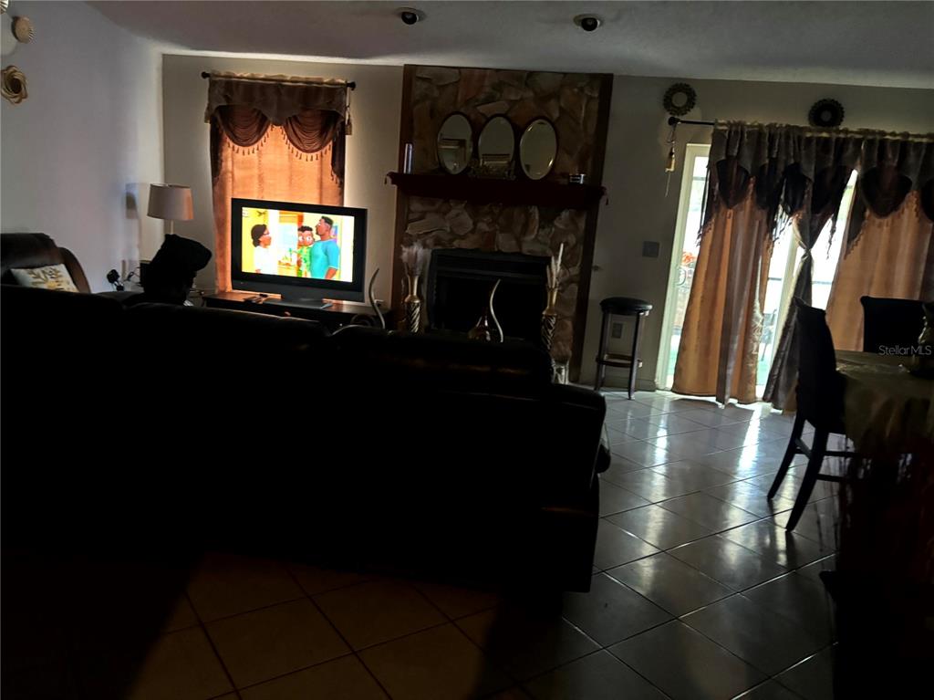 A living room features a stone fireplace, tile flooring, and a television on a stand — 1312 FOXBORO DR., BRANDON, FL