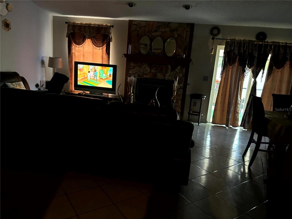 A living room features a stone fireplace, tile flooring, and a television on a stand — 1312 FOXBORO DR., BRANDON, FL