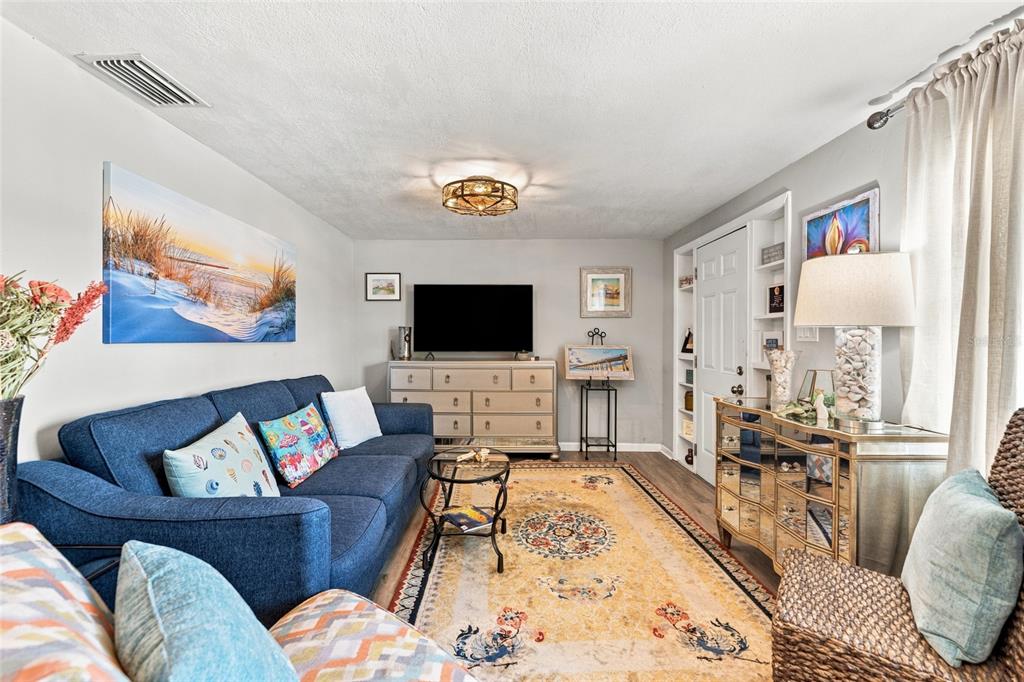 A living room features a blue sofa, a patterned area rug, and a mirrored console table — 3607 LATIMER STREET, NEW PORT RICHEY, FL