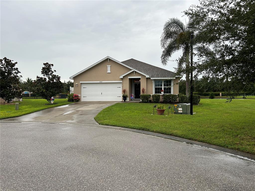 A single-story tan house with a two-car garage and a paved driveway — 25033 LALIQUE PLACE, PUNTA GORDA, FL