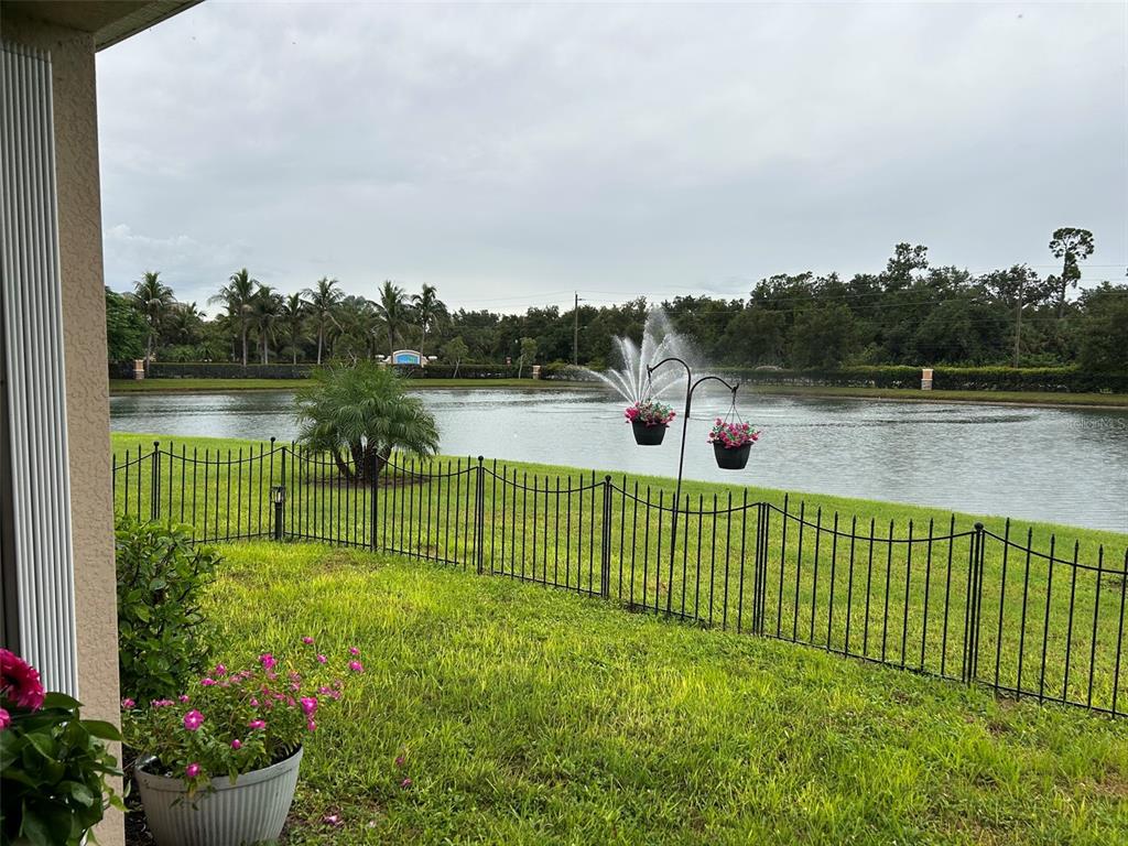 A view of a grassy backyard with a black metal fence overlooking a pond — 25033 LALIQUE PLACE, PUNTA GORDA, FL