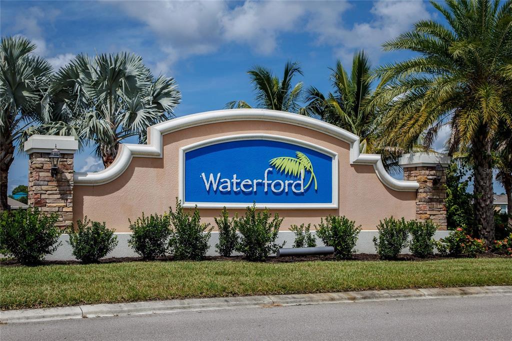 A beige stucco monument sign with stone pillars displays the name Waterford against palm trees — 25033 LALIQUE PLACE, PUNTA GORDA, FL
