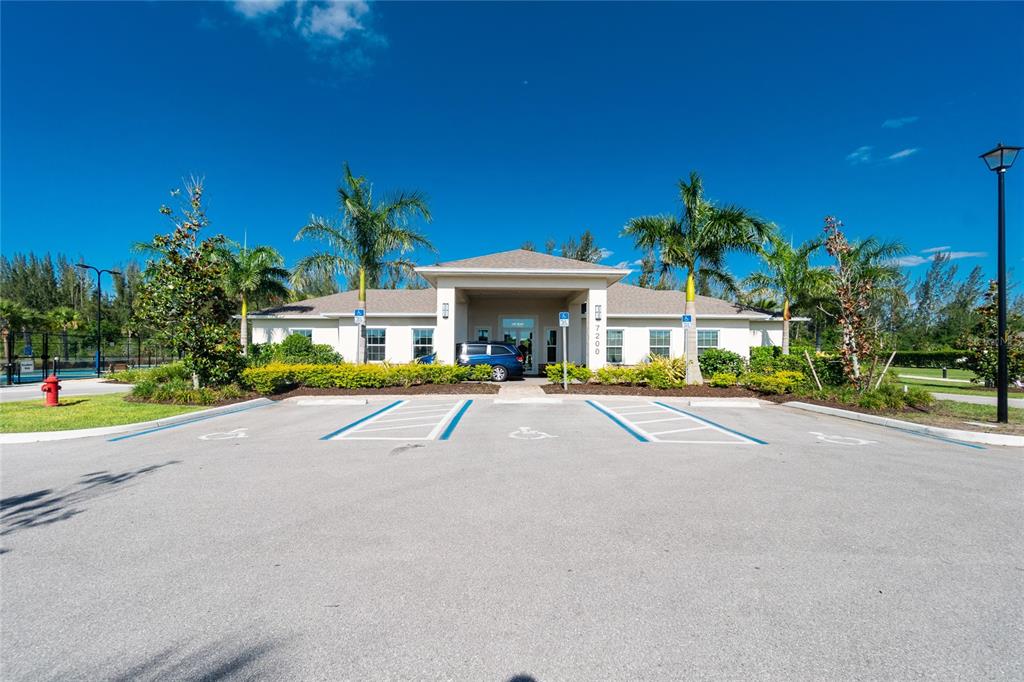 A single-story building with a covered entrance and parking lot under a clear blue sky — 25033 LALIQUE PLACE, PUNTA GORDA, FL
