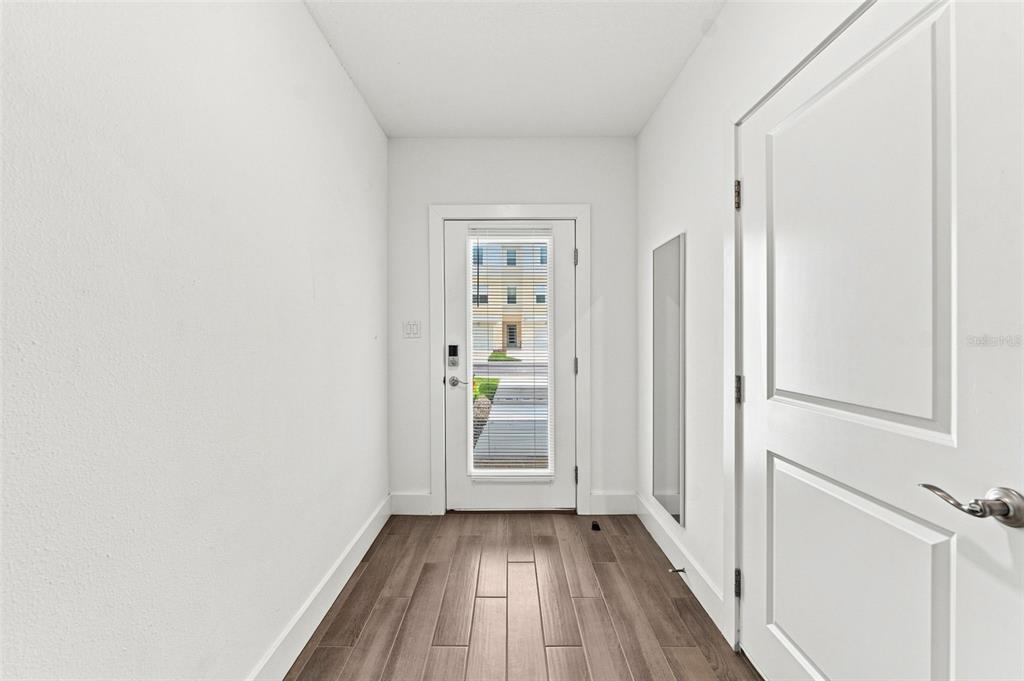 A bright entryway features white walls, wood-look flooring, and a door with a glass insert — 9939 KEY HAVEN ROAD, SEMINOLE, FL