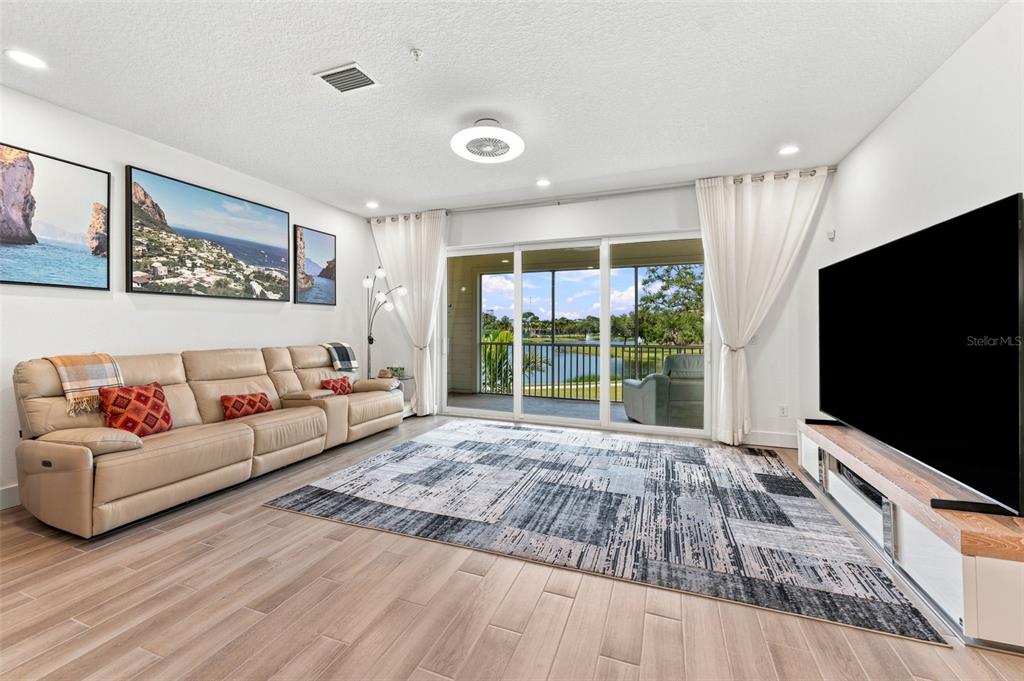 A living room features a beige leather sofa, a patterned area rug, and sliding glass doors — 9939 KEY HAVEN ROAD, SEMINOLE, FL