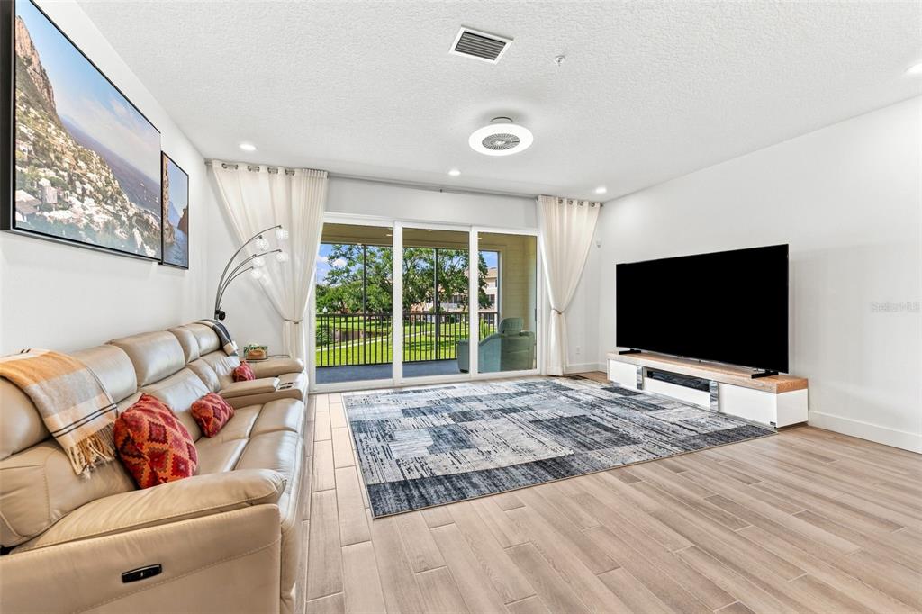 A living room features a leather sofa, large television, area rug, and sliding glass doors — 9939 KEY HAVEN ROAD, SEMINOLE, FL