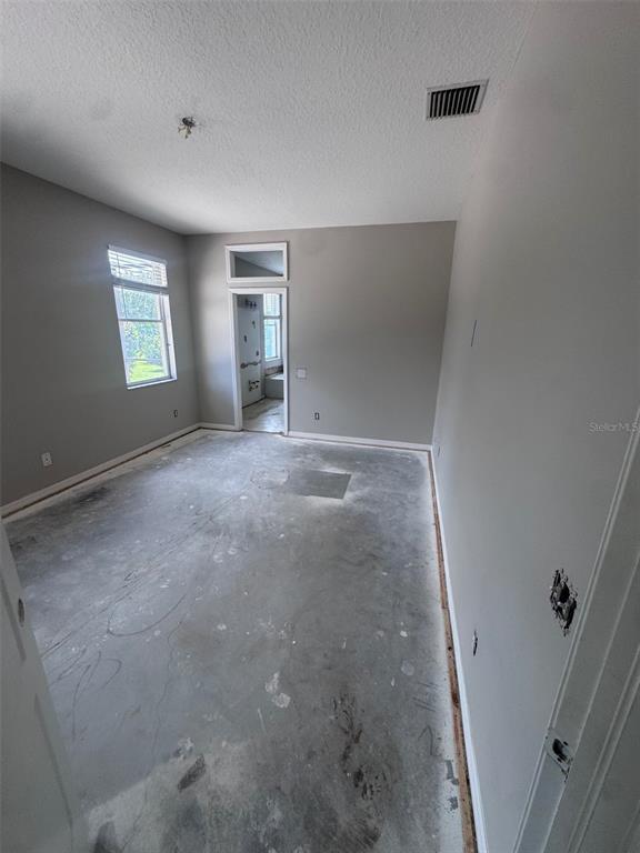 An unfinished room with gray walls, a concrete floor, and a doorway leading to another room — 1734 LADY PALM COURT, NEW PORT RICHEY, FL