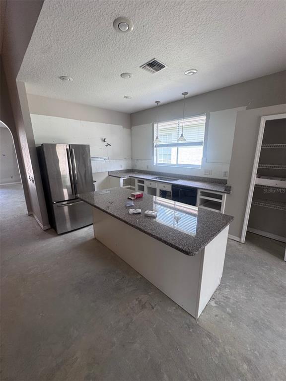 An unfinished kitchen features a granite-topped island, stainless steel refrigerator, and missing cabinet doors — 1734 LADY PALM COURT, NEW PORT RICHEY, FL