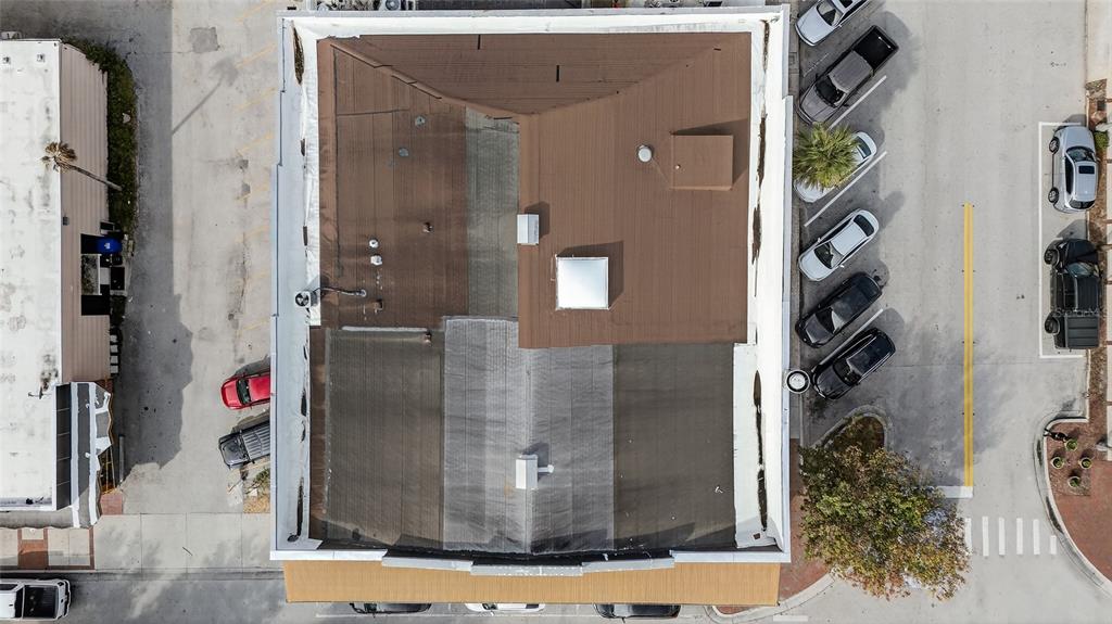 An aerial view shows the flat and sloped roof of a commercial building with parking — 219 BROADWAY, KISSIMMEE, FL