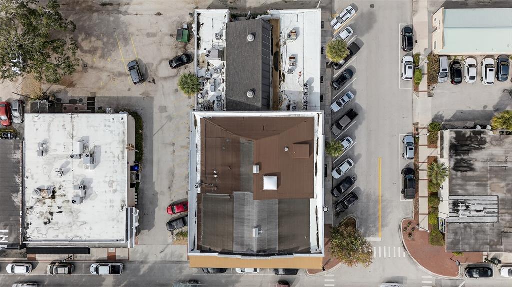 An aerial view shows a commercial building with a brown roof surrounded by parking lots — 219 BROADWAY, KISSIMMEE, FL