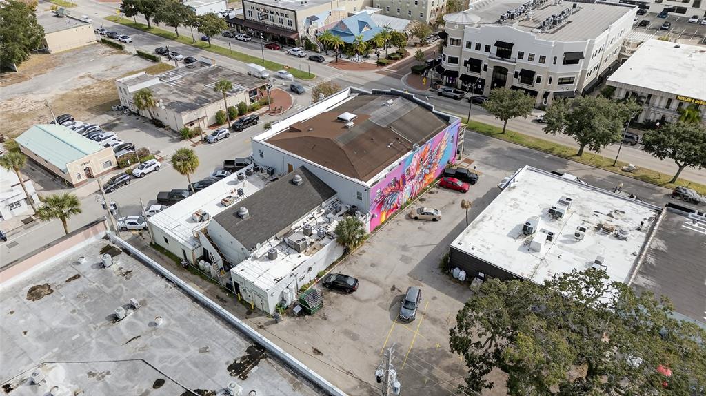 An aerial view shows a commercial building with a colorful mural and adjacent parking lot — 219 BROADWAY, KISSIMMEE, FL