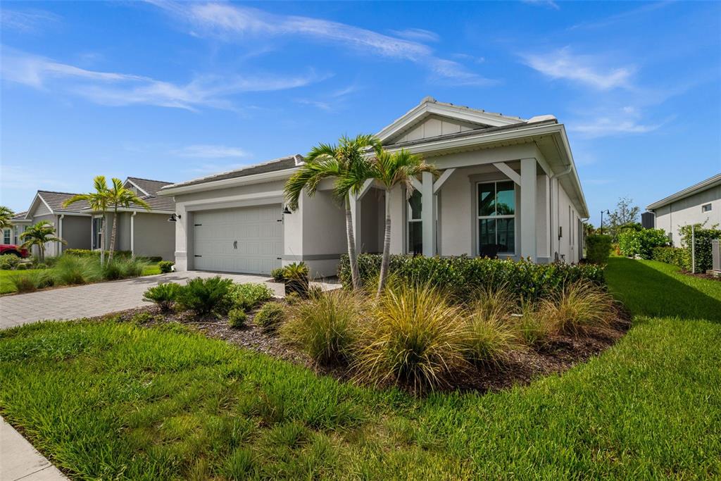 A single-story house with a two-car garage, palm trees, and landscaping under a blue sky — 12461 BASALT LANE, ALVA, FL
