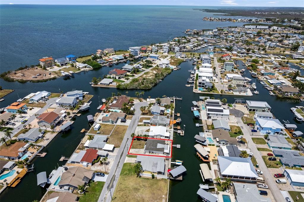 An aerial view shows a residential property outlined in red within a waterfront canal community — 13804 MALCOLM AVENUE, HUDSON, FL