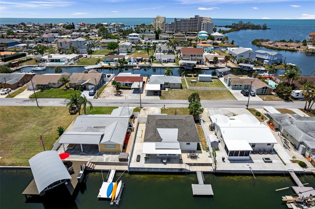 An aerial view shows waterfront houses with private docks along a canal near the ocean — 13804 MALCOLM AVENUE, HUDSON, FL