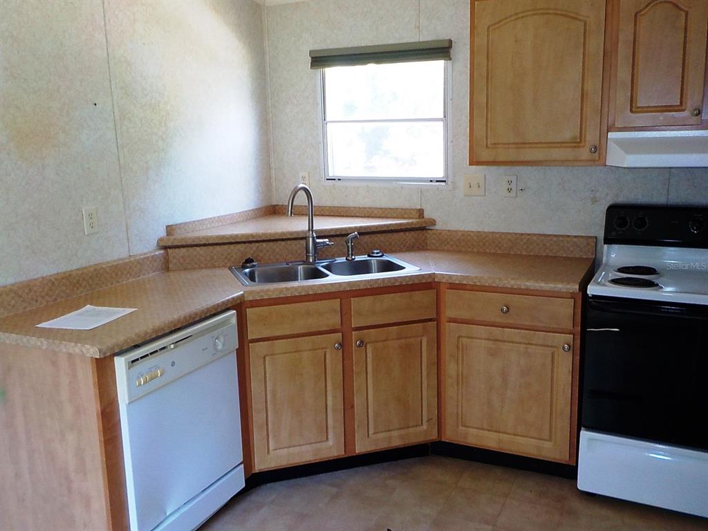 A kitchen features light wood cabinets, laminate countertops, a double sink, and white appliances — 7398 SW NORMAC DRIVE, ARCADIA, FL