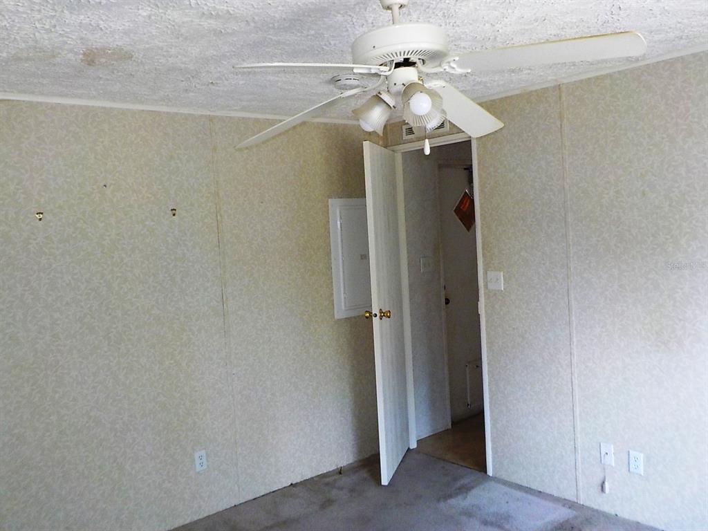 A room with patterned wallpaper, a ceiling fan, and an open door leading to another space — 7398 SW NORMAC DRIVE, ARCADIA, FL