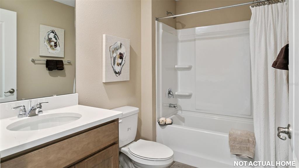 A bathroom features a white vanity, a toilet, and a white shower-tub combination — 63 HARDWOOD TRAIL, PALM COAST, FL