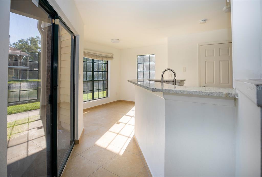 A kitchen with a granite breakfast bar, tile flooring, and a sliding glass door — 8711 FANCY FINCH DRIVE UNIT 101, TAMPA, FL